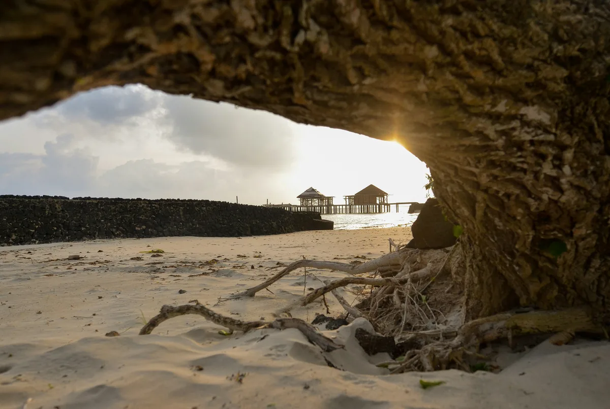 Brown wooden house on white sand under white clouds during daytime