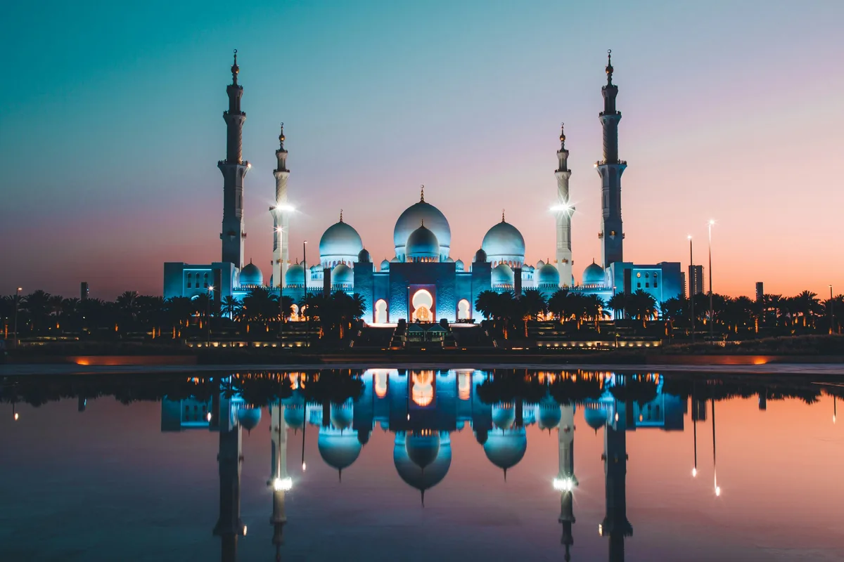 The Sheikh Zayed Grand Mosque reflected in a pool at low sun in Abu Dhabi