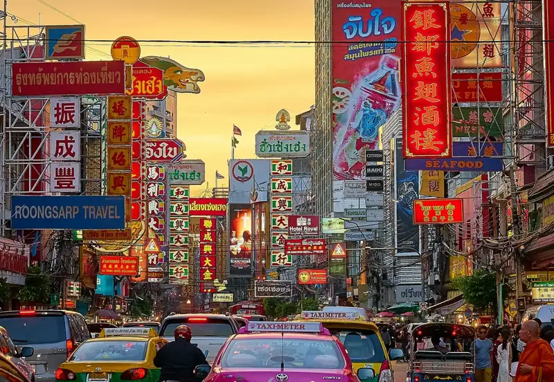 Vehicles on street between buildings with Kanji script signage during golden hour