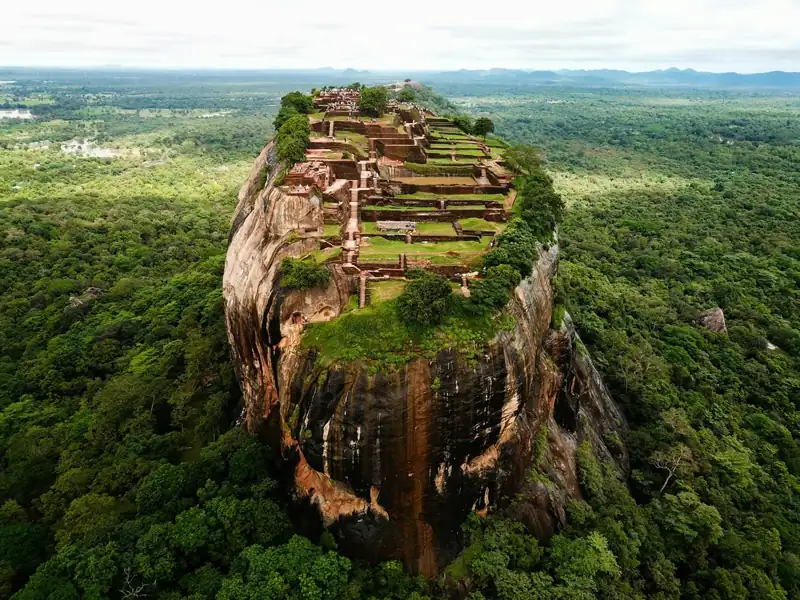 Aerial view of the Sigiriya rock fortress rising above a dense green forest