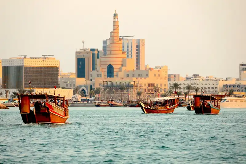 A group of boats in a body of water with buildings in the background