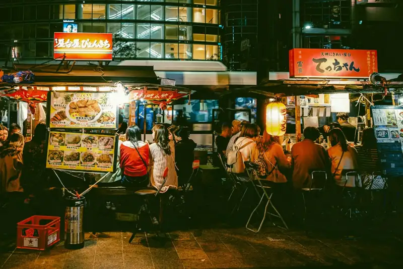 A group of people standing around a food stand