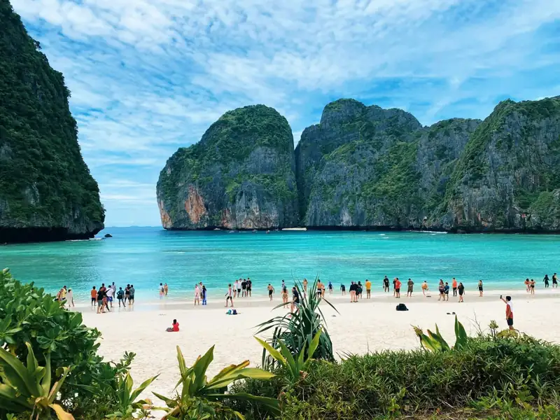 A group of people standing on top of a sandy beach