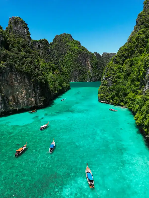 Longtail boats on the turquoise water of Pileh Lagoon surrounded by limestone cliffs