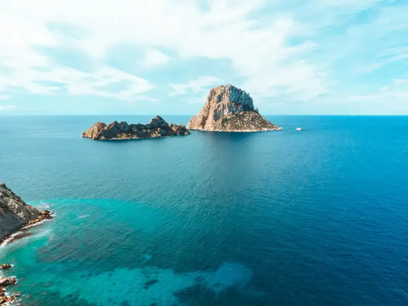 Gray and brown rock formation on blue sea under blue sky during daytime