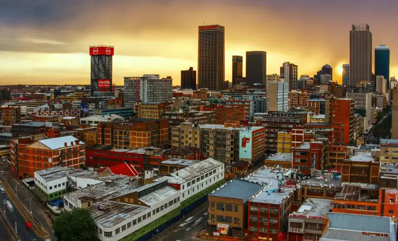 High-angle view of the Johannesburg skyline under a warm golden hour sky