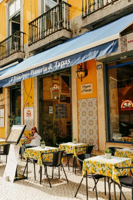 Outdoor seating at a vibrant yellow pizzeria with lemon tablecloths