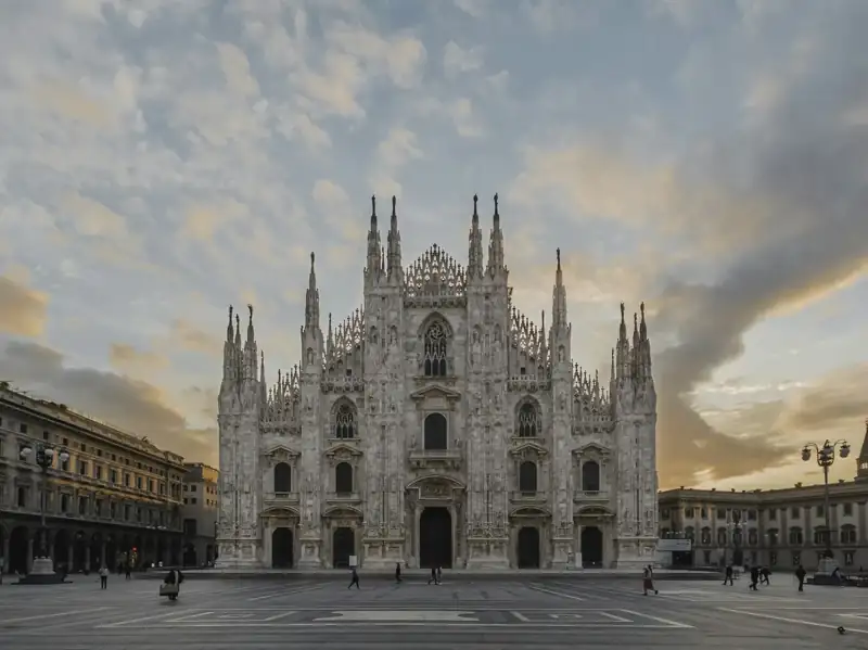 The Duomo di Milano cathedral in Milan under a soft orange and blue sky