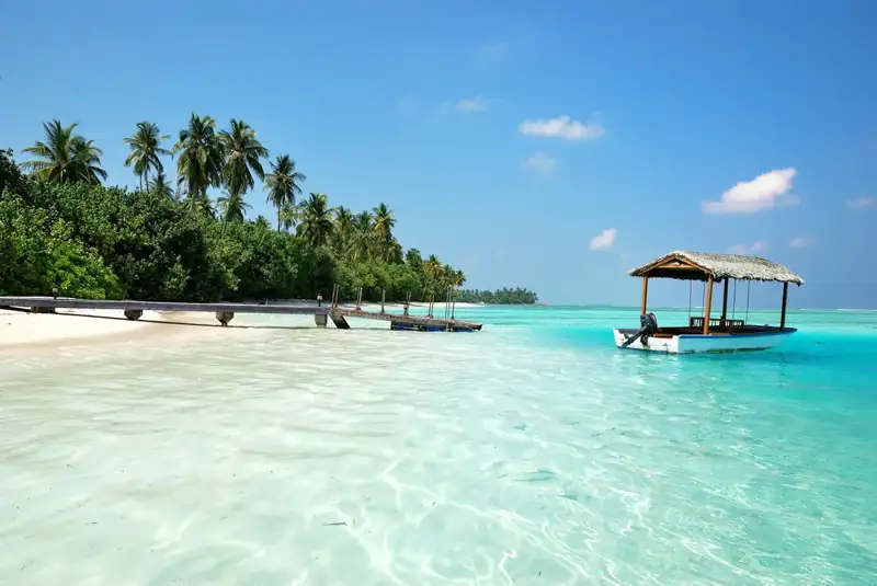A wooden pier and a thatched boat in the turquoise water of the Maldives