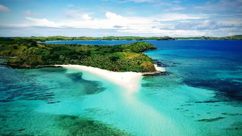 A beach with blue water and green land