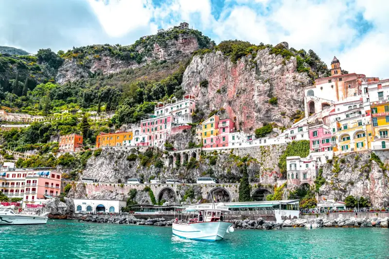 Colorful buildings on a rocky cliffside above the turquoise water in Amalfi, Italy