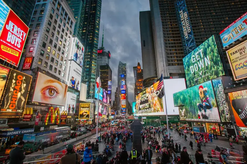 Crowds of people walking through Times Square in New York City at dusk