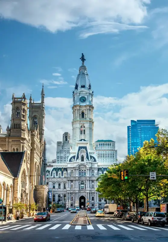 Philadelphia City Hall tower rising above a street with cars and a crosswalk
